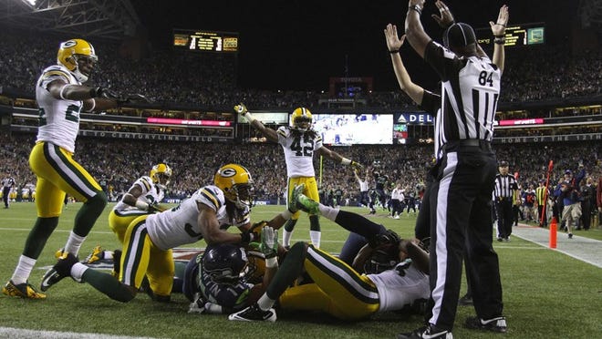 Two officials give different calls -- one signaling touchdown and the other starting to signal a touchback -- on a last-second pass into the end zone in a game between the Seahawks and Packers on Monday, Sept. 24, 2012, in Seattle. Officials ruled that both Seattle's Golden Tate and Green Bay's M.D. Jennings had possession of the ball simultaneously and awarded Seattle the game-winning score, setting off a firestorm among league observers and fans.