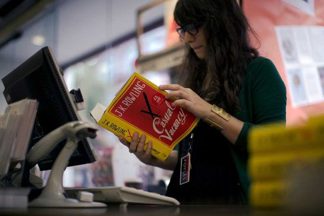 An employee looks at a copy of the "The Casual Vacancy" by author J.K. Rowling at a book store in London, Thursday, Sept. 27, 2012. British bookshops are opening their doors early as Harry Potter author J.K. Rowling launches her long anticipated first book for adults.