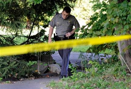 State Trooper Matt Losh emerges from the backyard of a home in New Fairfield, Conn., where a fatal shooting took place.