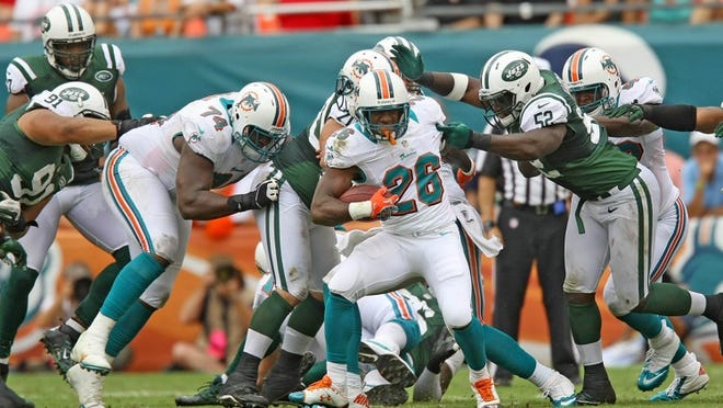 092412 (Bill Ingram/Palm Beach Post): Miami Gardens: Miami Dolphins running back Lamar Miller runs through the New York Jets defense during second half action at Sun Life stadium Sunday in Miami Gardens.