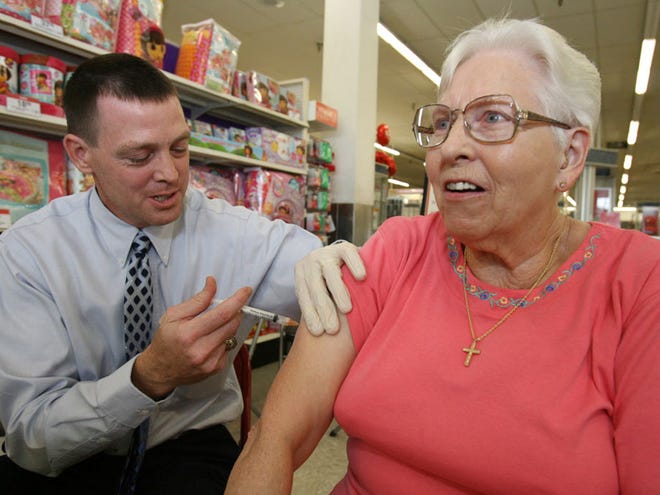 Louise Hall of Belleview, right, gets a flu shot from pharmacist James Mauller, left, at the KMART on South U.S. Highway 441 in Belleview, Fla.