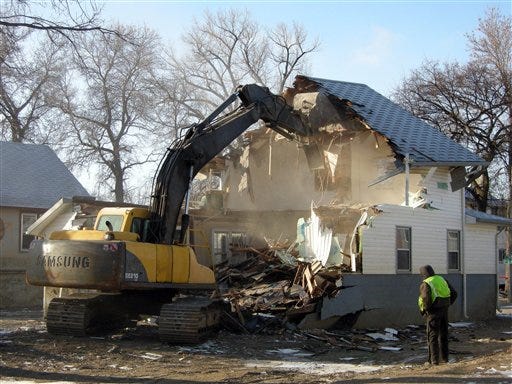 This Jan. 17, 2012, photo shows Magnum Demolition of Boise, Idaho, demolishing a flood-damaged house in Minot, N.D. People who bought flooded lots after houses were demolished received a surprise recently when they discovered they are on the hook for demolition costs.