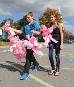 East Bridgewater High School students Caitlin Ward and Benjamin White carry pink ribbons to places around town. Cancer survivor Janet Cheney and students from East Bridgewater High School’s Key Club hung the ribbons to publicize the start of National Breast Cancer Awareness Month.