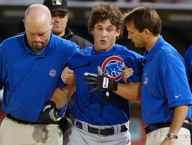 This July 9, 2005 file photo shows Chicago Cubs rookie Adam Greenberg, center, being helped by Cubs trainers after being hit in the helmet by the first pitch he faced in the major leagues.