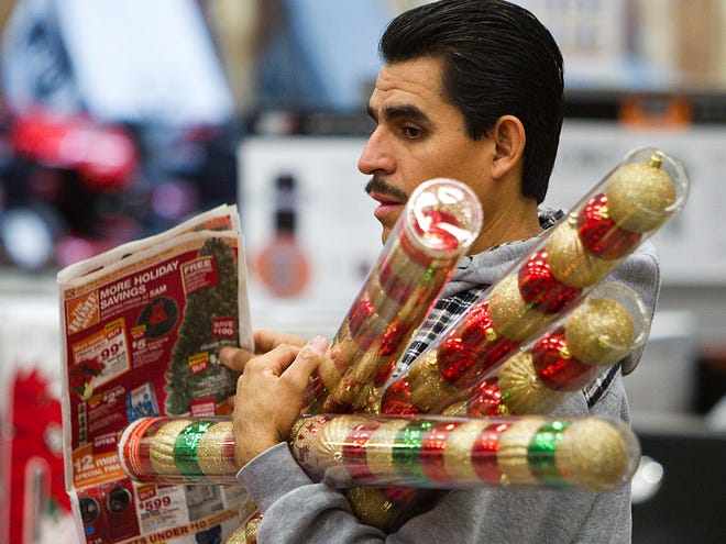 In this Friday, Nov. 25, 2011 file photo, Sergio Lira, of Phoenix, holds Christmas bulbs as he shops at the Home Depot in Phoenix. (AP Photo/Arizona Republic, Tom Tingle)