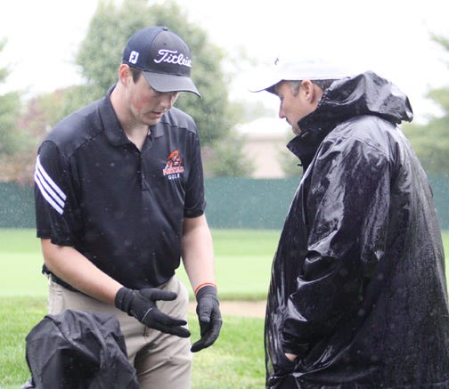 A cold and wet Aaron Jiles of Pontiac speaks with coach Paul Ritter after finishing the ninth hole at the Champaign (Central) Regional Tuesday.