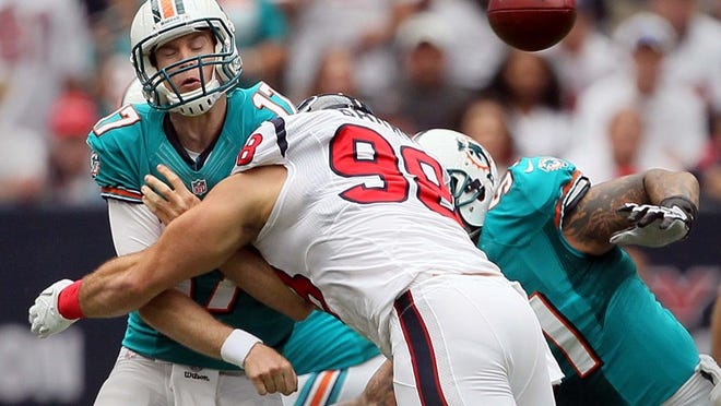 090912 Miami Dolphins quarterback Ryan Tannehill (17) gets rid of the ball before getting hit by Houston Texans defensive end J.J. Watt (99) in the first quarter at Reliant Stadium in Houston, Texas on Sept. 9, 2012. (Allen Eyestone/The Palm Beach Post)