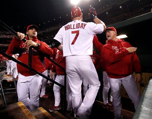 St. Louis Cardinals' Matt Holliday is congratulated by manager Mike Matheny, left, and hitting coach Mark McGwire, right, after driving in a run with a sacrifice fly during the first inning of a baseball game against the Cincinnati Reds on Tuesday, Oct. 2, 2012, in St. Louis. (AP Photo/St. Louis Post-Dispatch, Chris Lee)