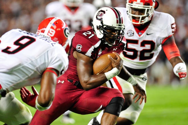 South Carolina Gamecocks running back Marcus Lattimore (21) runs with the ball while defended by Georgia Bulldogs linebacker Alec Ogletree (9) and Georgia Bulldogs linebacker Amarlo Herrera (52) during the NCAA college football game between the Georgia Bulldogs and the University of South Carolina Gamecocks in Columbia, S.C., Sat., Oct. 6, 2012. (AJ Reynolds/Staff)