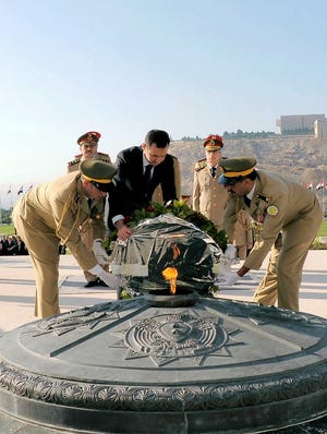 In this photo released by the Syrian official news agency SANA, Syrian President Bashar Assad lays a wreath Saturday at the tomb of the unknown soldier marking the anniversary of the 1973 Arab-Israeli war in Damascus, Syria.