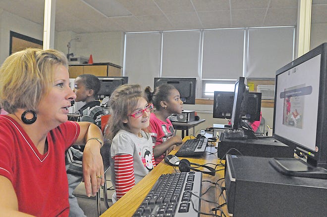 Galligan Elementary School reading teacher Carey Perkson, left, works with Catherine McDonough and Branalysa Varela as they read books on the computer for Read for the Record on Thursday.