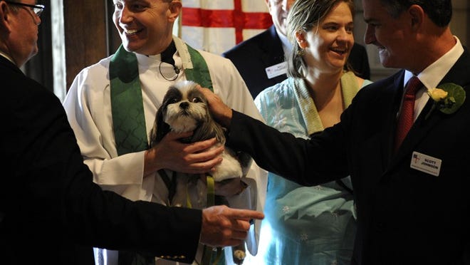 Usher Scott Johnson (right) pets Rev. James Harlan's dog Ranger after annual St. Francis of Assisi blessing of the animals service on Sunday at The Episcopal Church of Bethesda-by-the-Sea.