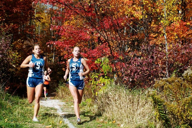 Sault High’s Rachel Cook, left, and Missy Zenker, right, run out of the woods at the William Lynn Trails during the Sault Elks Invitational Saturday.