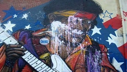 Someone splattered paint over the eyes of the hybrid Barack Obama/Jimi Hendrix figure on a mural on the side of a Quincy Center bar.