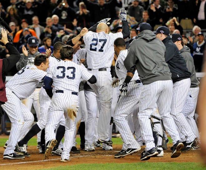 New York Yankees' Raul Ibanez (27) celebrates with teammates as he reaches home plate after hitting the game-winning home run during the 12th inning of Game 3 of the American League division baseball series against the Baltimore Orioles on Wednesday, Oct. 10, 2012, in New York. The Yankees won 3-2. (AP Photo/Bill Kostroun)