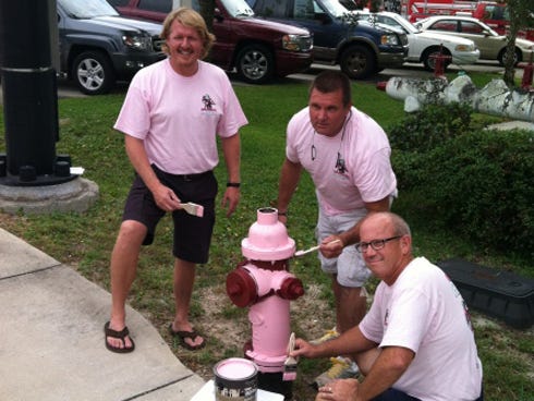 (From left to right) Commissioner Ken Scoper, Commissioner Mike Buckingham and Commissioner Jack Wilson put the finishing touches on the first pink fire hydrant of the day.