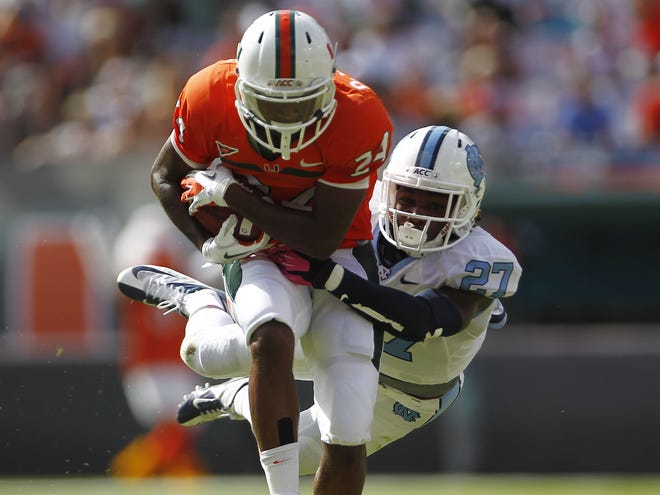 Miami's Davon Johnson (24) is stopped by North Carolina's Darien Rankin (27) after running for a first down during the first half of Saturday's game in Miami.