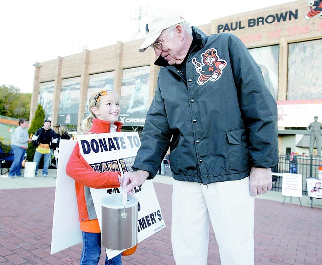 Frank Gibson puts a check into the bucket of 8-year-old Grace Muzi before the Massillon Tiger game Friday. Muzi and others were taking donations as part of Team Tiger for her grandfather, Jim Letcavits, and the Alzheimer’s Walk this weekend.