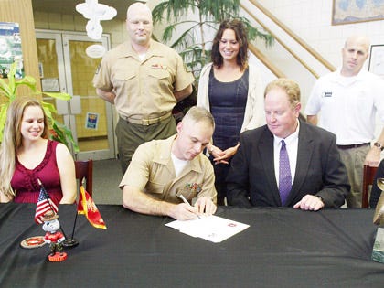 Lt. Col. Ryan Goulette, second from left, commanding officer of Marine Aviation Logistics Squadron 14 at Cherry Point, signs the Adopt-a-School agreement next to Havelock High Principal Jeff Murphy, as other school and military representatives look on. MALS-14 Marines will volunteer at the school with such things as the NJROTC program, Crystal Coast Band Classic and with campus beautification and school improvement projects.