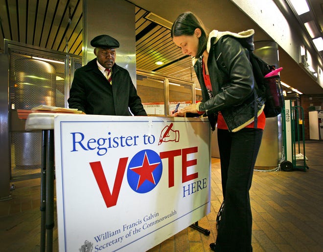 Molly Caslin registers to vote at the Quincy Adams MBTA station Thursday, Oct. 11, 2012. The secretary of state’s voter registration stand was being staffed by Calvin Brown. Caslin needed to change her registration because she had moved from Quincy to Weymouth.