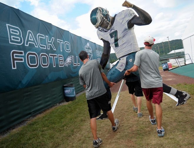 Philadelphia Eagles marketing interns Sean Gale, left, and Kyle Heckelman carry a large cutout of Eagles quarterback Michael Vick to a spot Saturday afternoon, July 21, 2012, as staff members finish up preparations for the NFL football team's training camp, which begins Monday. (AP Photo/The Express-Times, Matt Smith)