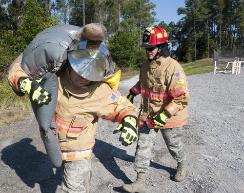 U.S. Air Force Chief Master Sgt. Brian Richardson, command chief of 1st Special Operations Mission Support Group (left) and Col. Douglas Dudley, commander of 1st SOMSG, work together to carry a 75-pound mannequin to safety during training on Hurlburt Field, Oct. 11. The Hurlburt Field Fire Department gave its first-ever crash course on the firefighter’s daily training regiment to the 1st SOMSG squadron leadership.