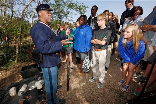 Skylar Patterson, right, Christopher Develle, second from right, and Brycelynn Kelly, all 13, listen as Patrick Shell of Vicksburg, Miss., left, discusses the life of a colored Union soldier and their importance during the Civli War, Friday, Oct. 19, 2012 in Raymond, Miss. As part of a four-day observance of the 150th anniversary of the Battle of Raymond, reenactors spent the first two days teaching school children about the local historical involvement in the conflict, about the life led by a regular soldier, about firing a cannon, and provided examples of surviving in the caves that dotted the hills around Vicksburg during the siege.