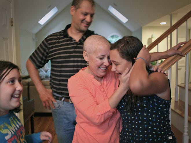 Elise DeCola, center, rubs heads with her daughter Emma, 11, as husband Pete and daughter Sofia, 8, look on, in their Plymouth home Tuesday, Oct. 2, 2012. DeCola, 42, is facing breast cancer a second time and recently finished chemotherapy that caused her hair to fall out.