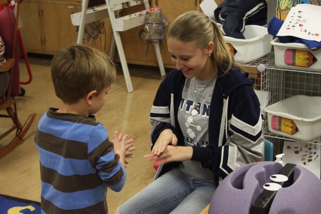 Monmouth-Roseville senior Kelly Dupre shows Lincoln kindergarten student Dylan Reynolds how to rub on glow lotion that simulates germs. Reynolds later placed his hands under the light of the Glitterbug Handshow before and after washing his hands to show the difference handwashing makes. Dupre gave hand washing demostrations last week as part of an internship at the Warren County Health Department.