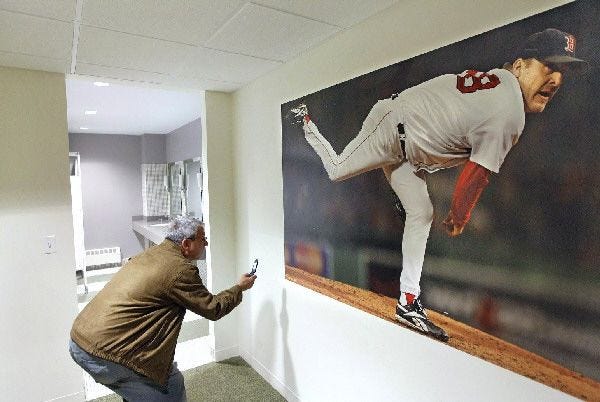 Lew, choosing only to give his first name, takes a picture Tuesday of the Curt Schilling "bloody sox" poster hanging in the second-floor men's restroom and locker room during an auction of the remnants of the former Boston Red Sox pitcher's video gaming company, 38 Studios, in Providence, R.I.