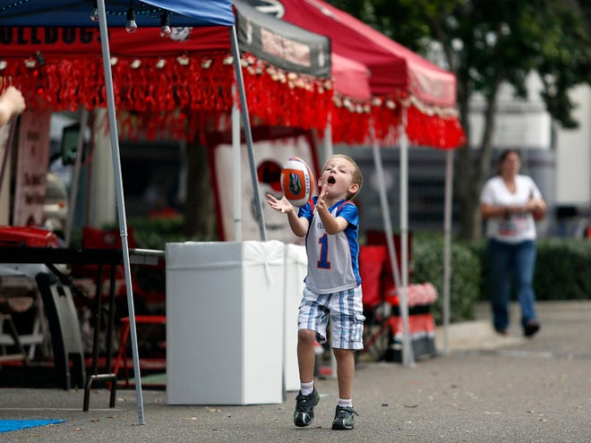 Mason Curts, 5, plays catch while at RV City as folks arrive early for the Florida versus Georgia football game in Jacksonville Thursday.( Erica Brough}/Staff Photographer )