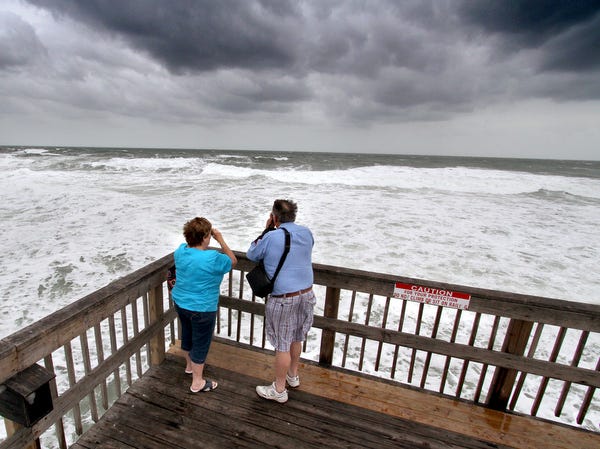 David and Lynn Tennant of California snap photos of the waves generated by Hurricane Sandy as they roll ashore from the end of the Sunglow Pier in Daytona Beach Shores on Friday.