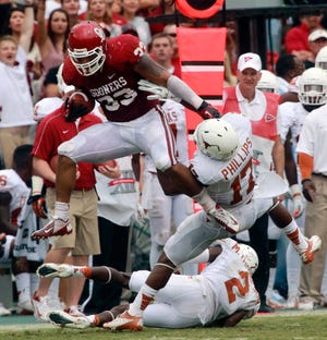 Oklahoma fullback Trey Millard (33) breaks a tackle against Texas cornerback Adrian Phillips (17) and defensive back Mykkele Thompson (2) during the first half of an NCAA college football game at the Cotton Bowl in Dallas on Oct. 13.   Millard continues to take on a bigger role for No. 8 Oklahoma, going from being a blocker to a threat as a runner and pass-catcher. His task this week: to try and neutralize standout Notre Dame linebacker Manti Te'o. (AP Photo/Michael Mulvey, File)