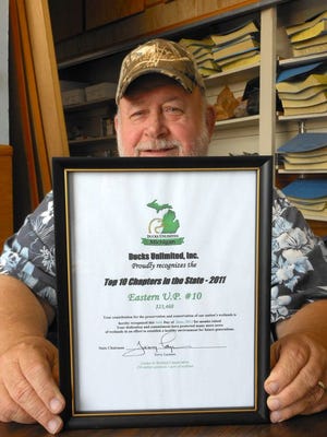 Chairman Dan Heuer of the Eastern Upper Peninsula Chapter of Ducks Unlimited proudly displays a Top Ten award from the organization. In raising $23,468 last year, the local chapter successfully competed with approximately 175 chapters in the state to earn the honor.