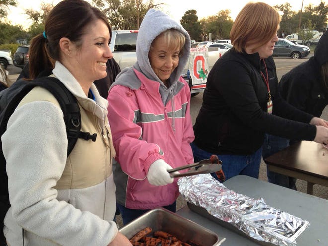 Tarran West, from left, Debbie Stone and Kim Hutchinson helped serve more than 2,000 hotdogs during the tailgate party at Travis Middle School on Thursday evening.