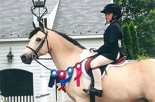 Erika Murphy sits atop Stormy and displays her blue and red ribbons.
