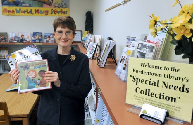 Beverly Jacob, Children's Librarian & Coordinator of Special Needs Collections & Programs, at the Bordentown Branch of the Burlington County Library System, stands with a couple of books from the collection.