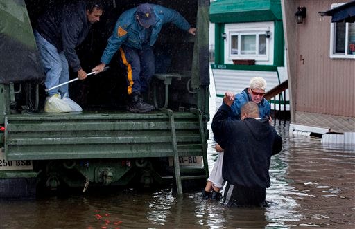 A woman is lifted into a National Guard vehicle after leaving her flooded home at the Metropolitan Trailer Park in Moonachie, N.J. Tuesday, Oct. 30, 2012, after supsterstorm Sandy. Sandy, which was downgraded from hurricane just before making landfall, caused multiple fatalities, halted mass transit and cut power to more than 6 million homes and businesses. (AP Photo/Craig Ruttle)