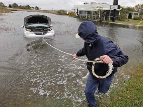 Glenn Heartley pulls on a rope attached to his car in preparation for getting it towed from a creek in Chincoteague, Va., Tuesday, Oct. 30, 2012. Heartley and his wife were swept off the road into the shallow creek during superstorm Sandy's arrival Monday.
