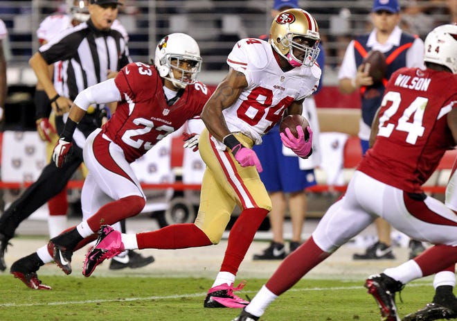 San Francisco 49ers wide receiver Randy Moss (84) runs in a 47-yard touchdown after a reception as Arizona Cardinals cornerback Jamell Fleming (23) pursues during the second half of an NFL football game, Monday, Oct. 29, 2012, in Glendale, Ariz.
