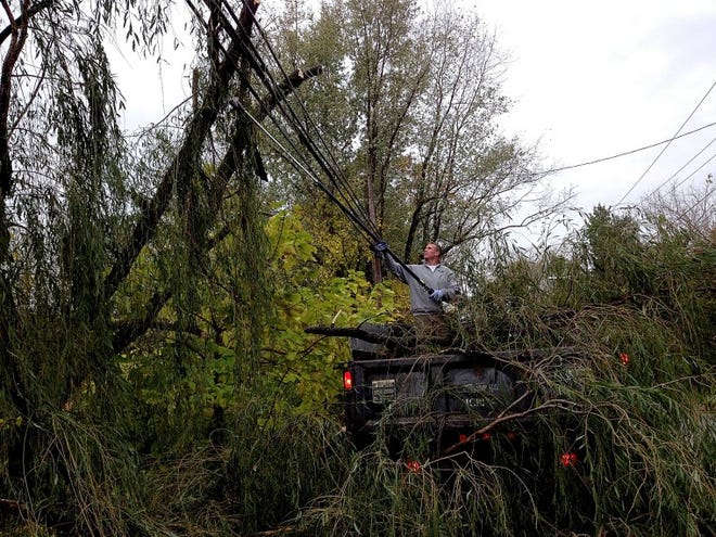 Brian Dixon of Medford clears a large tree branch from a utility wire along Union Road in Medford. Working for Allstate Landscaping of Medford, Dixon said he had received many calls for tree work by Tuesday morning.