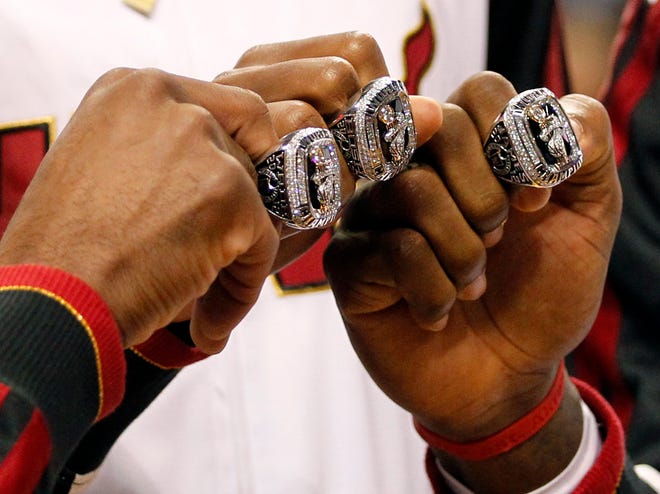 From left, the Miami Heat's Dwyane Wade, Chris Bosh and LeBron James pose with their 2012 NBA Finals championship rings during a ceremony before Tuesday night's game against the Celtics.