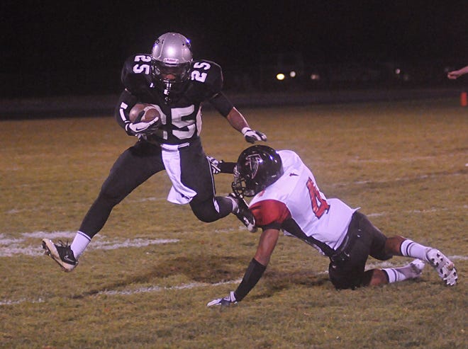 West Ottawa's James Lacy (25) breaks a tackle from Kentwood's Jalin Stoviall (4) Friday night.