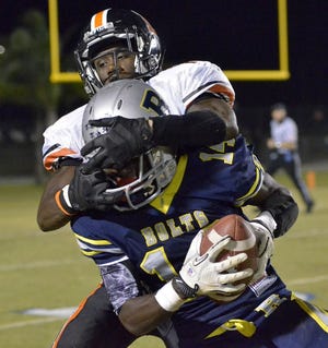 RIDGE COMMUNITY'S SHYKEEM PITTS pulls in an interception just before getting hit by Lakeland's Xavier Spann during Friday night's game. Pitts' late interception for a touchdown was the only score in the Bolts' upset win.
