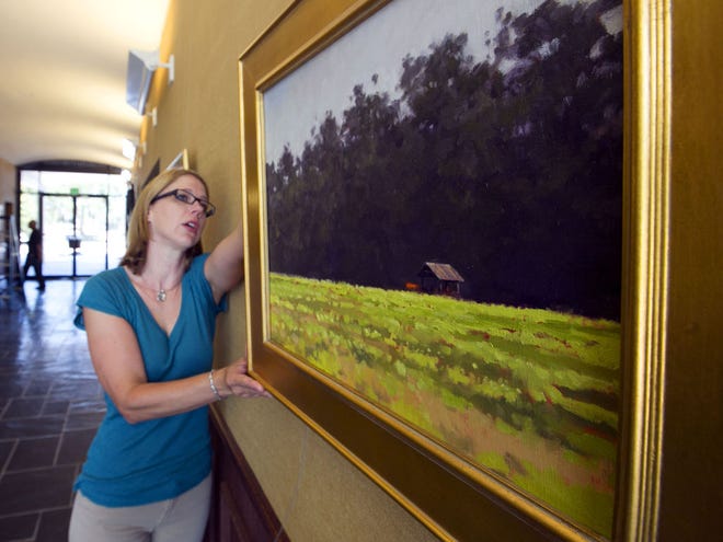 Melissa Townsend, Cultural Arts Coordinator for the City of Ocala, hangs artist Steve Andrews paintings in the first floor of the Ocala City Hall in Ocala in this July 9, 2012 file photo.