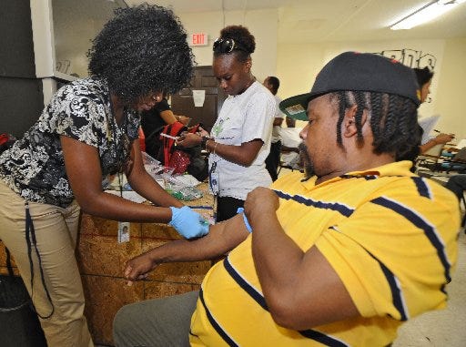 Duval County Health Department workers Jemima Govergo (left) and Shantrell Hudson conduct a tuberculosis test on Emery Handy Jr. in August. The TB surge in Duval's homeless population has spurred Orange County to do similar testing for their homeless.
