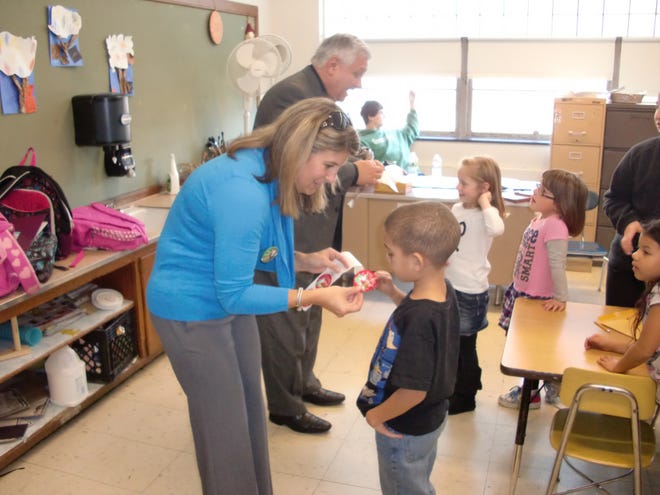 Taunton Area Chamber of Commerce President Kerrie Babin hands a Lights On sticker to Leddy Elementary School student Amare Perry.