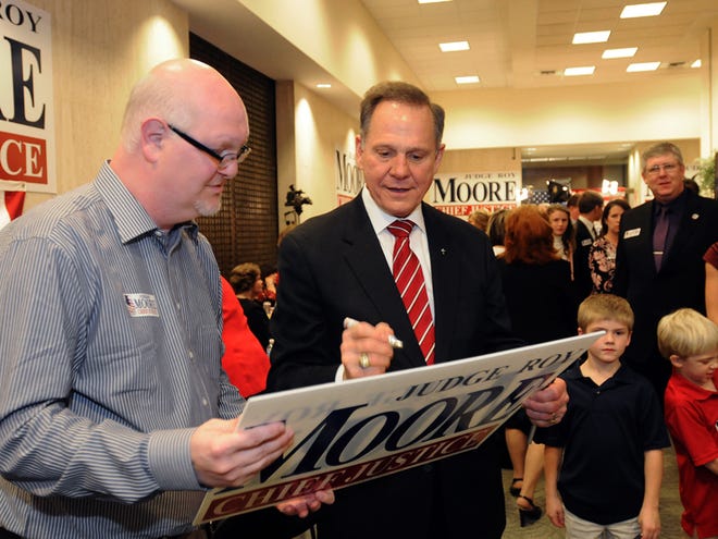 Roy Moore, right, candidate for Alabama Supreme Court chief justice, signs a poster for supporter Carey Black of Tuscaloosa at Moore's election party in Montgomery, on election night Tuesday.