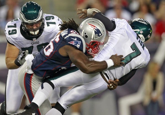 Patriots linebacker Jermaine Cunningham drops Eagles quarterback Michael Vick to the field on a hard hit during the first quarter Monday. Vick left the game after the play. At left is Philadelphia Eagles tackle Todd Herremans.