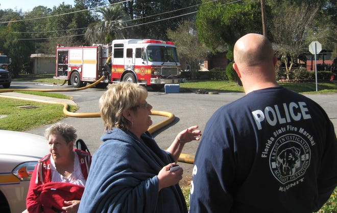 Homeowner Jan Vath speaks with an investigator after escaping an 8:30 a.m. Wednesday fire at her home on Lake Shore Boulevard. She and friend Connie Furr, seated, woke to an explosion but couldn't put out the flames.